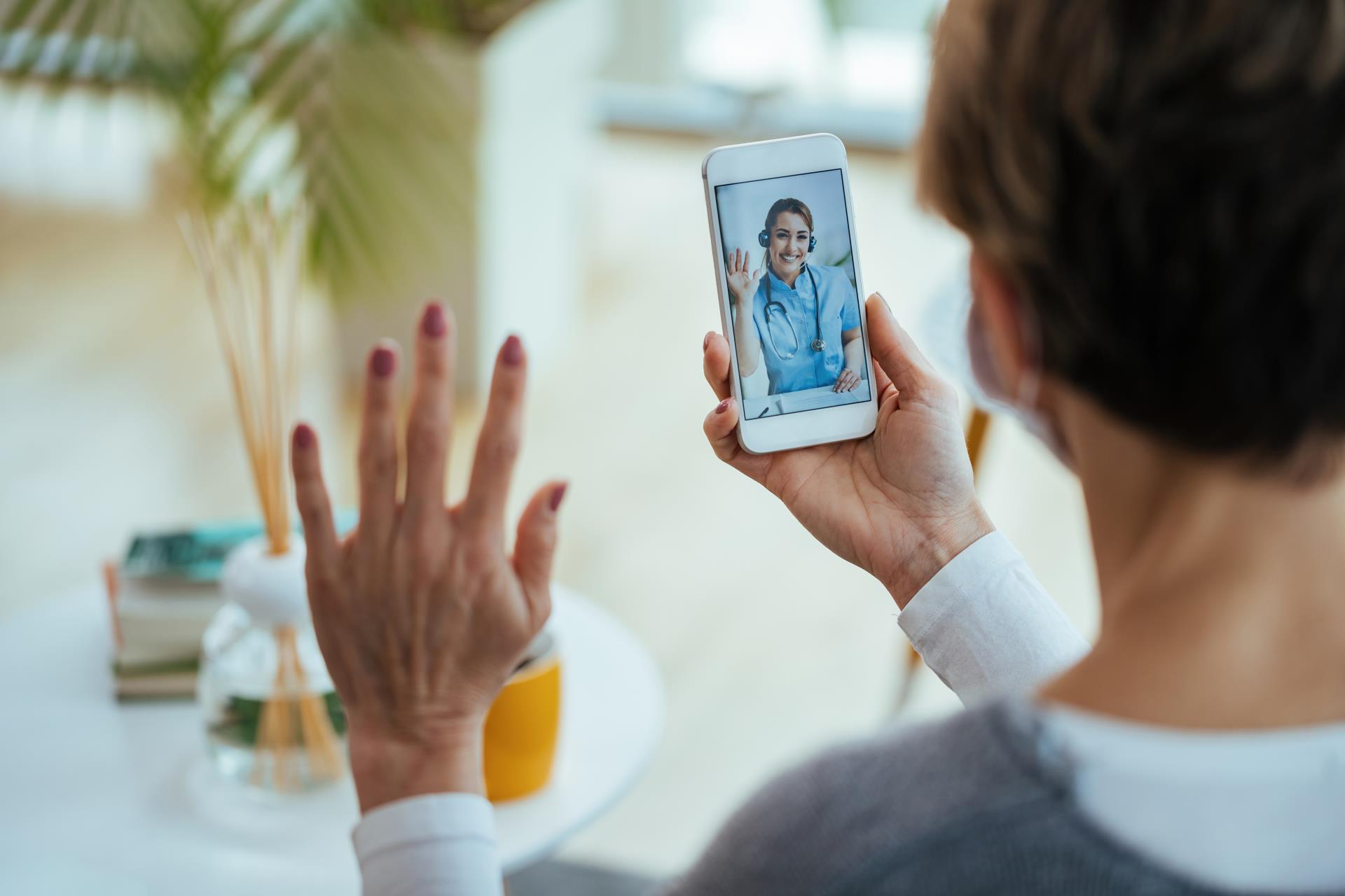 closeup-woman-greeting-her-doctor-while-using-smart-phone-having-video-call-focus-is-female-doctor-touchscreen