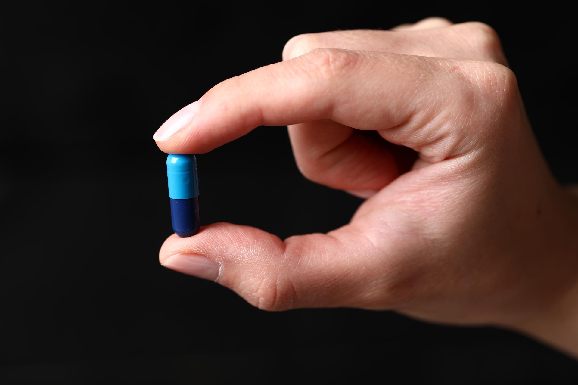 holding-blue-medical-pill-hand