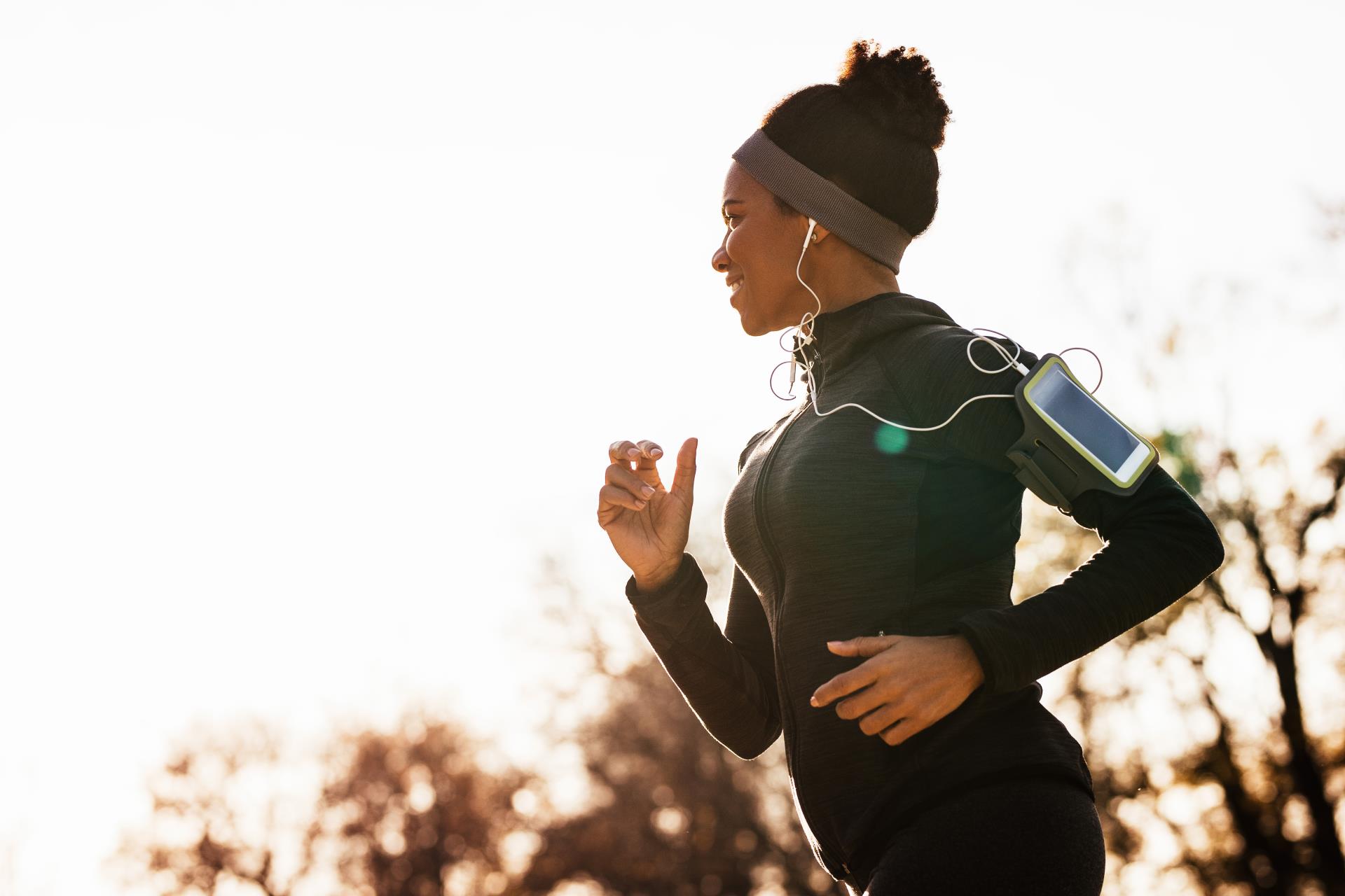 happy-african-american-woman-with-earphones-running-park