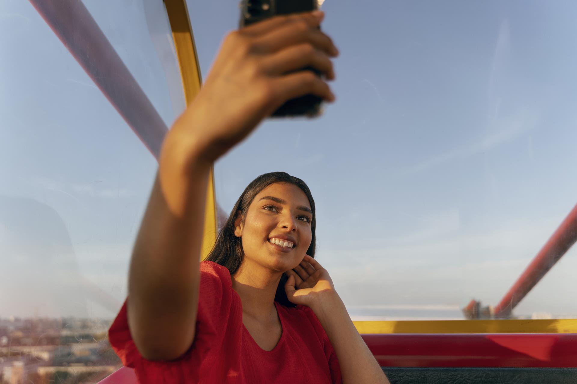 person-taking-selfie-with-smartphone-while-ferris-wheel