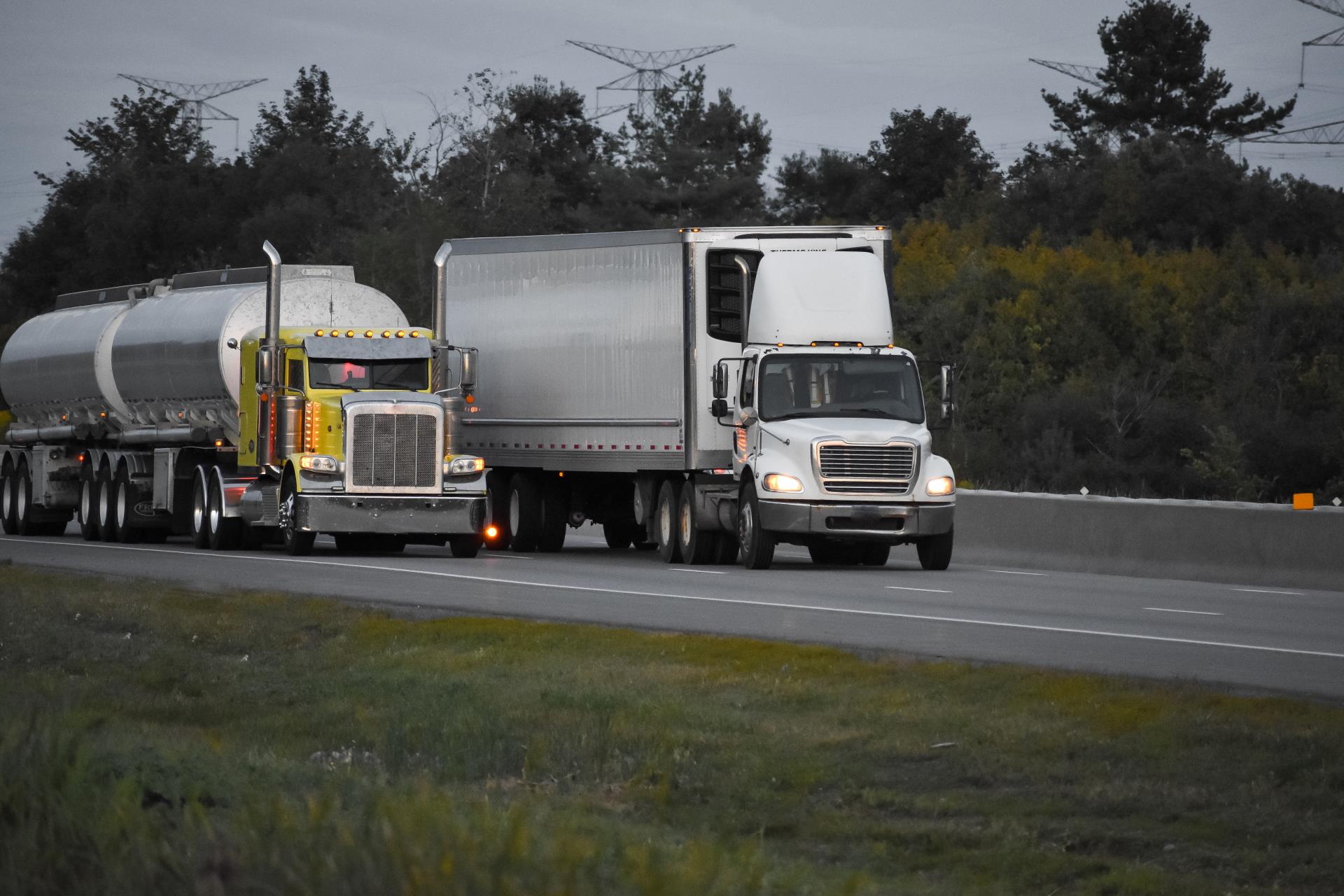 trailer-trucks-driving-road-surrounded-by-beautiful-green-trees