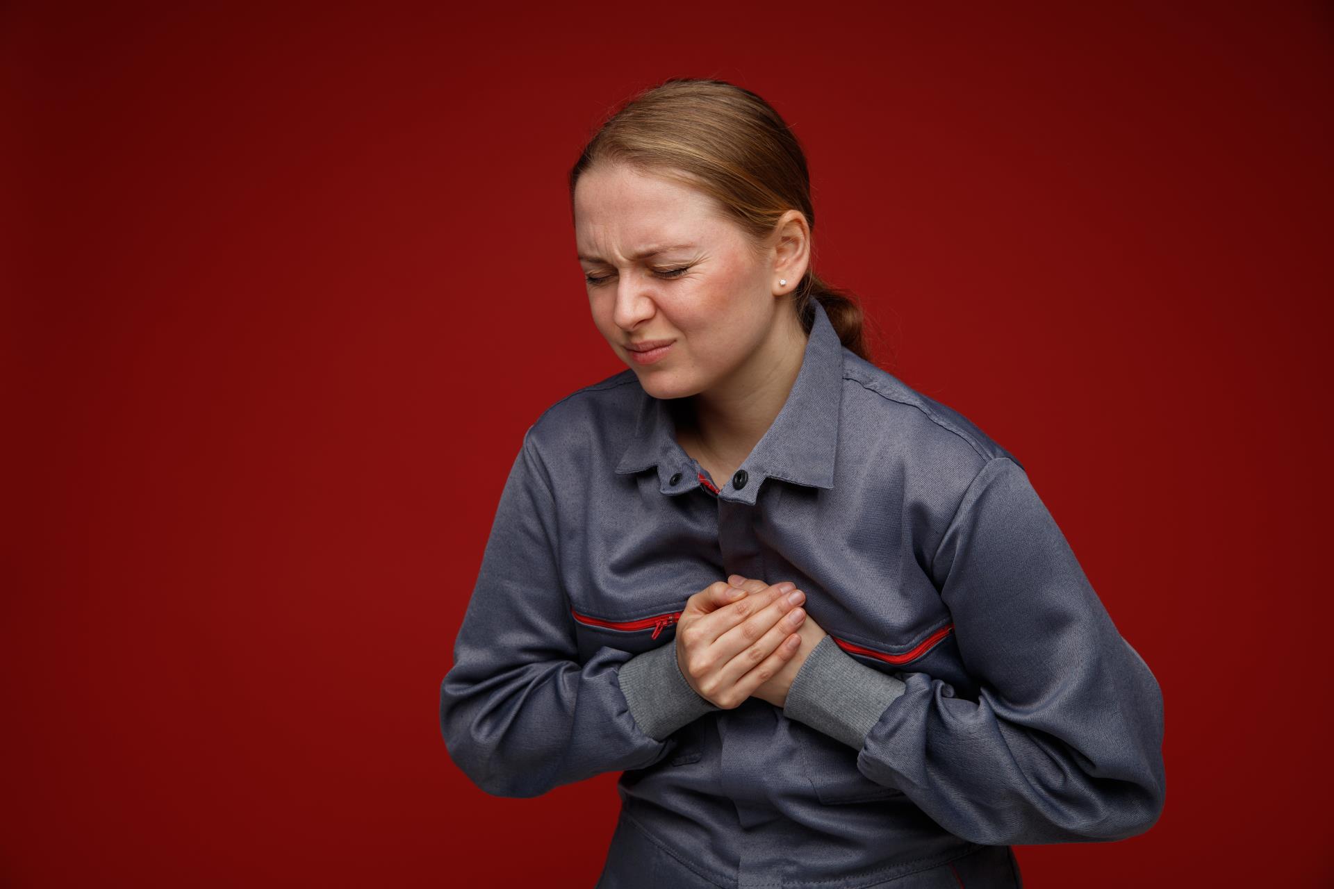 aching-young-blonde-female-engineer-wearing-uniform-keeping-hands-chest-with-closed-eyes