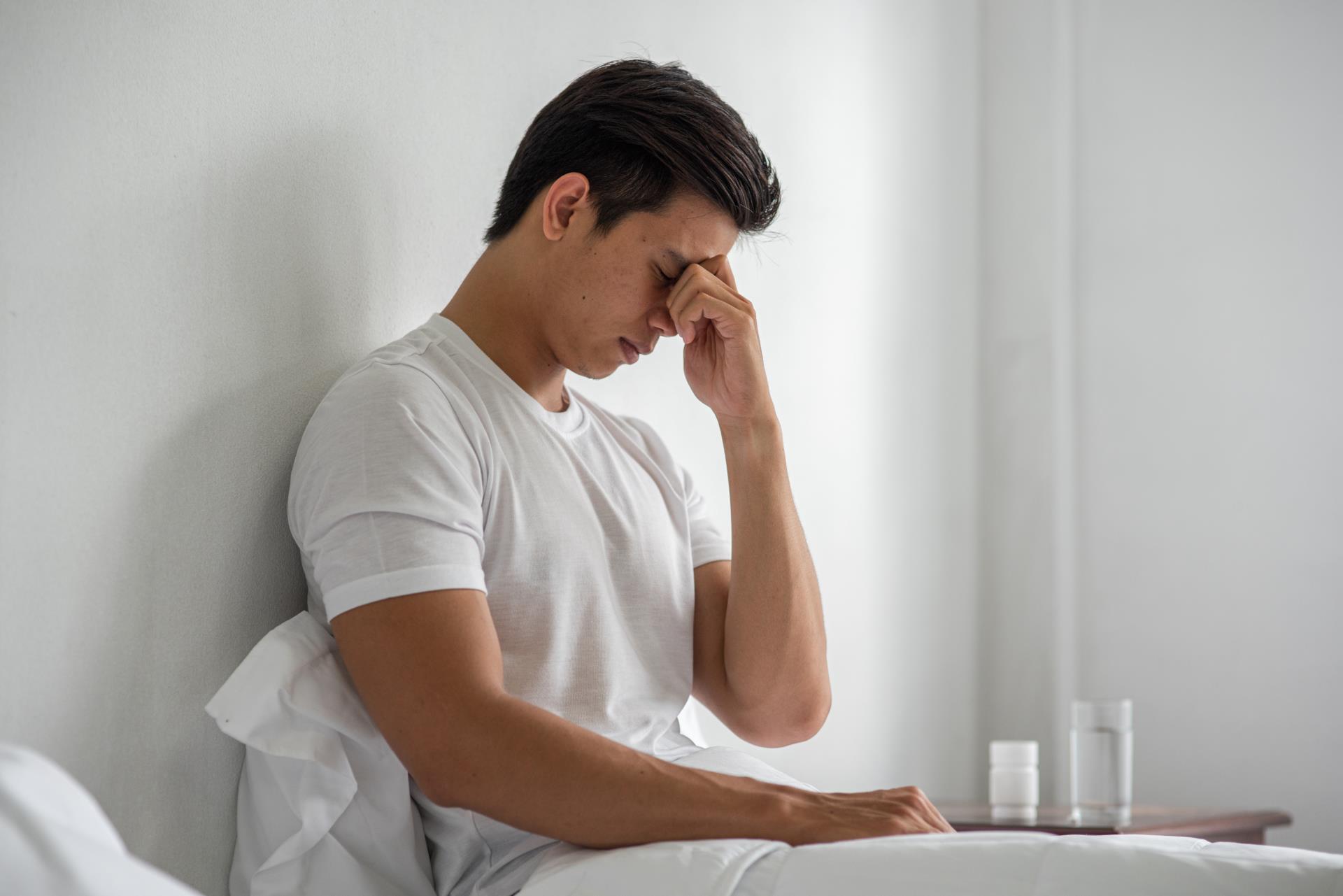 man-with-migraines-holds-her-hand-by-his-nose-bed