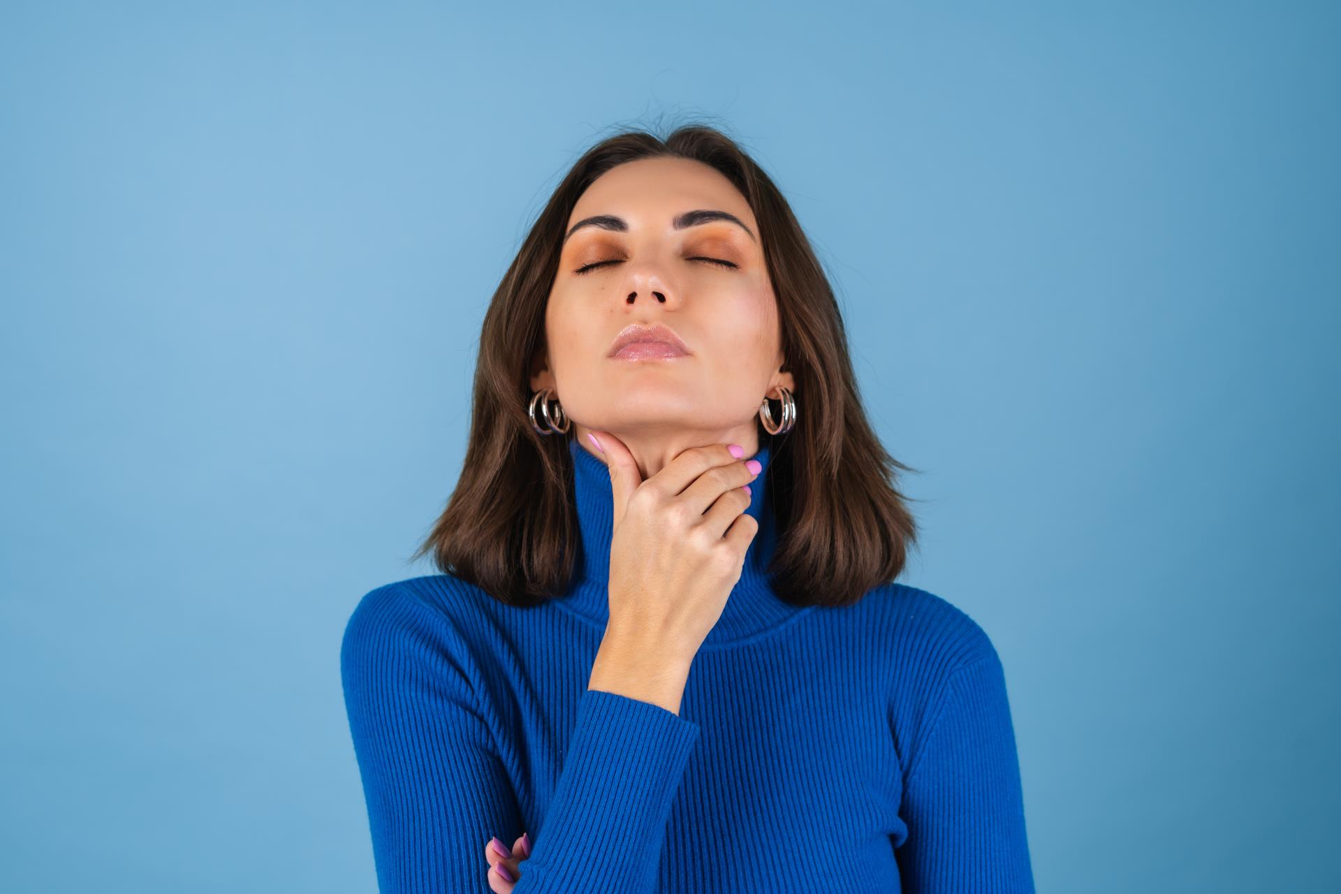 young-woman-blue-wall-touches-her-throat-suffers-from-pain