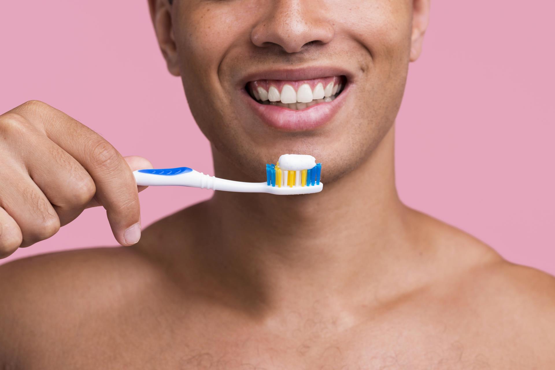 front-view-smiley-man-holding-toothbrush-with-toothpaste (1)