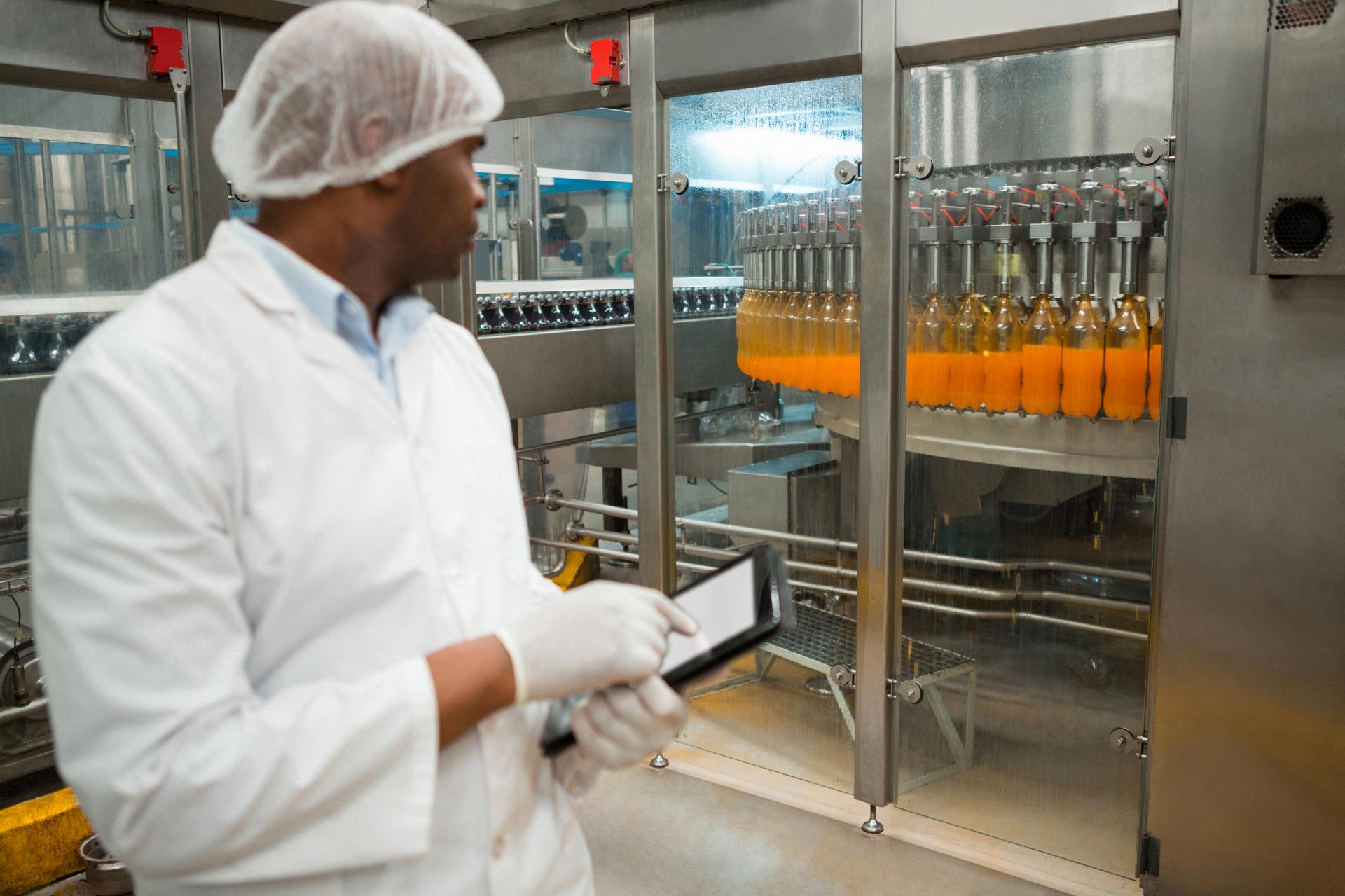 male-worker-inspecting-juice-bottles-factory