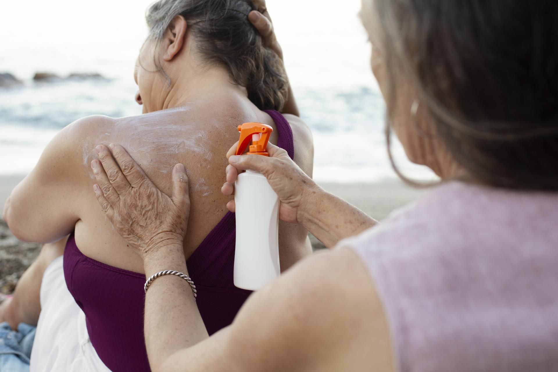 senior-women-applying-sunscreen-back-beach