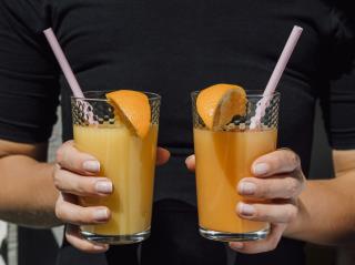 woman-dressed-black-holding-glasses-juice