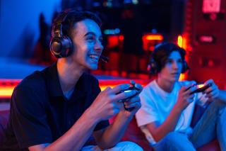 two-teen-friends-headphones-are-playing-game-console-using-gamepads-smiling