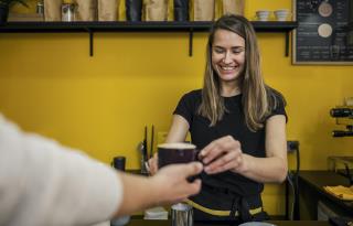 front-view-smiley-female-barista-handing-cup-coffee