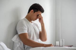 man-with-migraines-holds-her-hand-by-his-nose-bed
