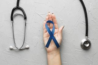 crop-hand-with-blue-ribbon-near-stethoscope